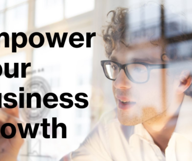 A promotional image featuring a blurred individual in the foreground with glasses and curly hair, looking towards text that reads “Empower Your Business Growth” in bold, black font on a translucent overlay.