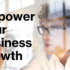 A promotional image featuring a blurred individual in the foreground with glasses and curly hair, looking towards text that reads “Empower Your Business Growth” in bold, black font on a translucent overlay.