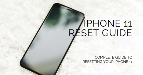 A black smartphone lying on a surface covered with white petals, displaying the text “IPHONE 11 RESET GUIDE"