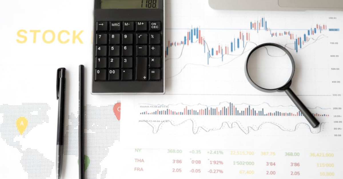 supply chain management . A flat lay image of a calculator, pen, pencil, magnifying glass, and financial documents with stock market data and a world map.