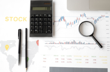 supply chain management . A flat lay image of a calculator, pen, pencil, magnifying glass, and financial documents with stock market data and a world map.