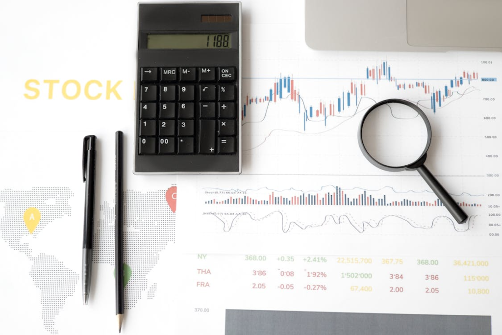supply chain management . A flat lay image of a calculator, pen, pencil, magnifying glass, and financial documents with stock market data and a world map.