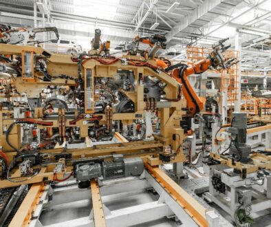 A large automation industrial factory with robotic arms automating the assembly of a car frame on an assembly line.